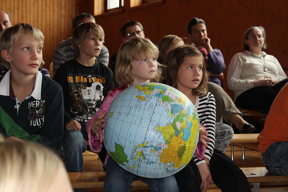 Kinder halten einen Globus-Luftballon in den Händen